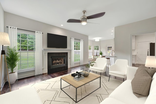 living room with ceiling fan, dark hardwood / wood-style floors, a healthy amount of sunlight, and a tile fireplace