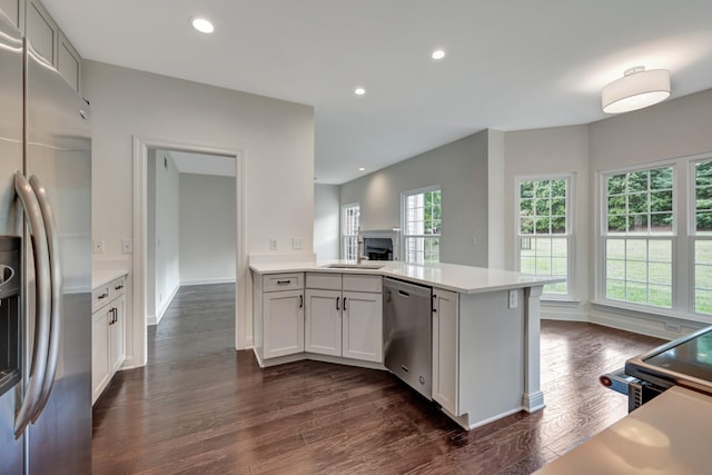 kitchen featuring dark hardwood / wood-style floors, white cabinetry, kitchen peninsula, and appliances with stainless steel finishes