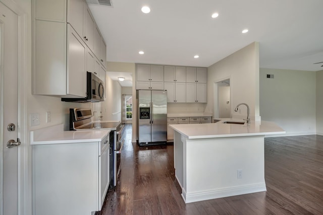 kitchen with dark hardwood / wood-style flooring, sink, stainless steel appliances, and an island with sink