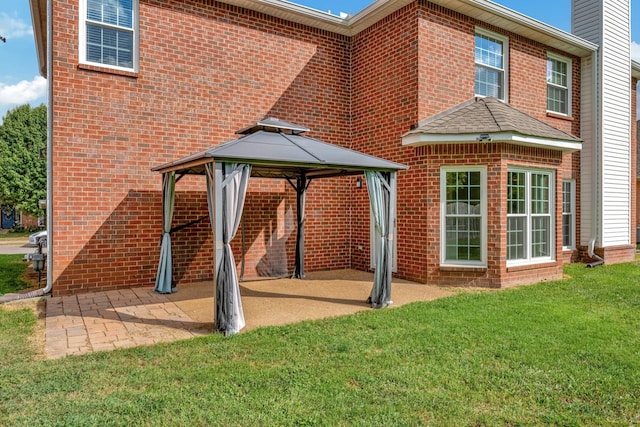 rear view of house featuring a gazebo, a patio, and a lawn