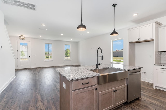 kitchen with light stone countertops, sink, stainless steel dishwasher, a center island with sink, and white cabinets