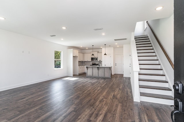 unfurnished living room featuring sink and dark hardwood / wood-style floors