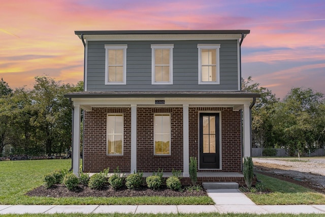 front facade featuring a yard and covered porch