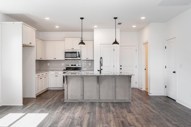 kitchen with white cabinetry, hanging light fixtures, light stone counters, a center island with sink, and appliances with stainless steel finishes