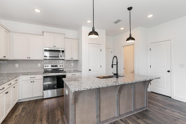 kitchen with light stone countertops, a kitchen island with sink, sink, and stainless steel appliances