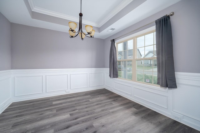 unfurnished room with a chandelier, a raised ceiling, and crown molding