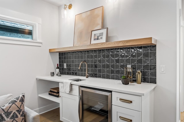 bar with sink, wine cooler, decorative backsplash, white cabinetry, and wood-type flooring