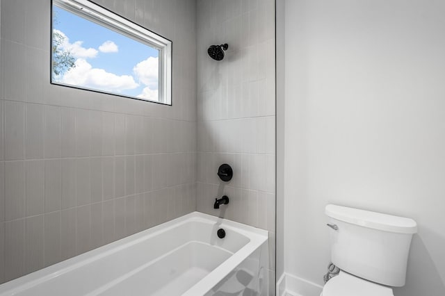 bathroom with tiled shower / bath combo and toilet