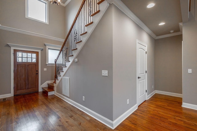 entrance foyer featuring ornamental molding, a notable chandelier, and hardwood / wood-style flooring