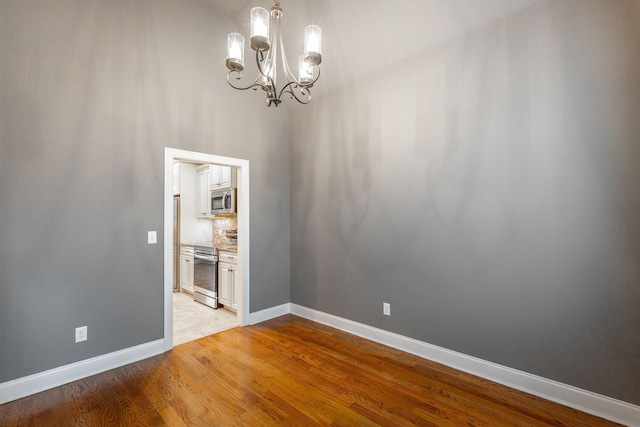 empty room featuring light hardwood / wood-style flooring and a chandelier