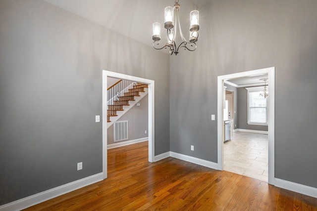 spare room with wood-type flooring and a notable chandelier