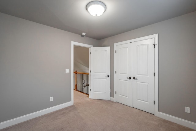 unfurnished bedroom featuring light carpet and a closet