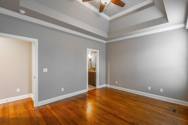 empty room featuring a tray ceiling, hardwood / wood-style floors, and ornamental molding