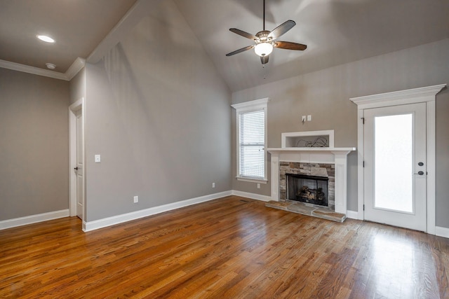 unfurnished living room featuring lofted ceiling, a stone fireplace, crown molding, ceiling fan, and wood-type flooring