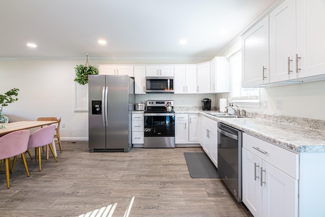 kitchen with white cabinetry, stainless steel appliances, sink, light wood-type flooring, and crown molding
