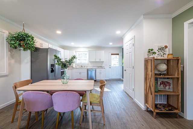 dining room with hardwood / wood-style flooring, sink, and ornamental molding