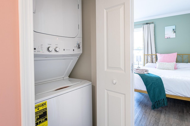 clothes washing area with ornamental molding, stacked washer / drying machine, and hardwood / wood-style flooring