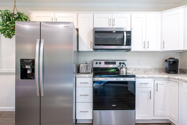 kitchen featuring appliances with stainless steel finishes, white cabinetry, dark hardwood / wood-style floors, ornamental molding, and light stone counters
