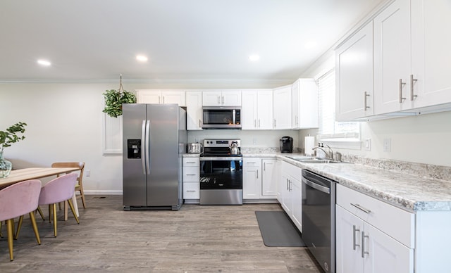 kitchen with sink, crown molding, stainless steel appliances, and white cabinetry