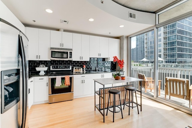 kitchen featuring white cabinets, a center island, light hardwood / wood-style floors, and appliances with stainless steel finishes