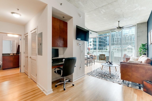 office space with ceiling fan, floor to ceiling windows, light hardwood / wood-style floors, and electric panel