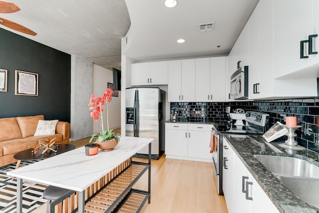 kitchen with ceiling fan, stainless steel appliances, tasteful backsplash, white cabinets, and light wood-type flooring