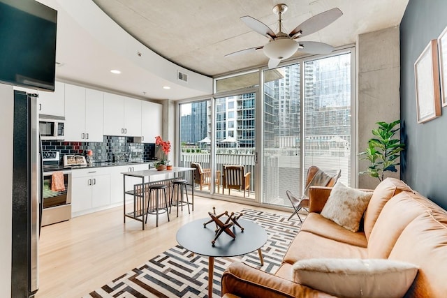 living room featuring light hardwood / wood-style floors, expansive windows, and ceiling fan