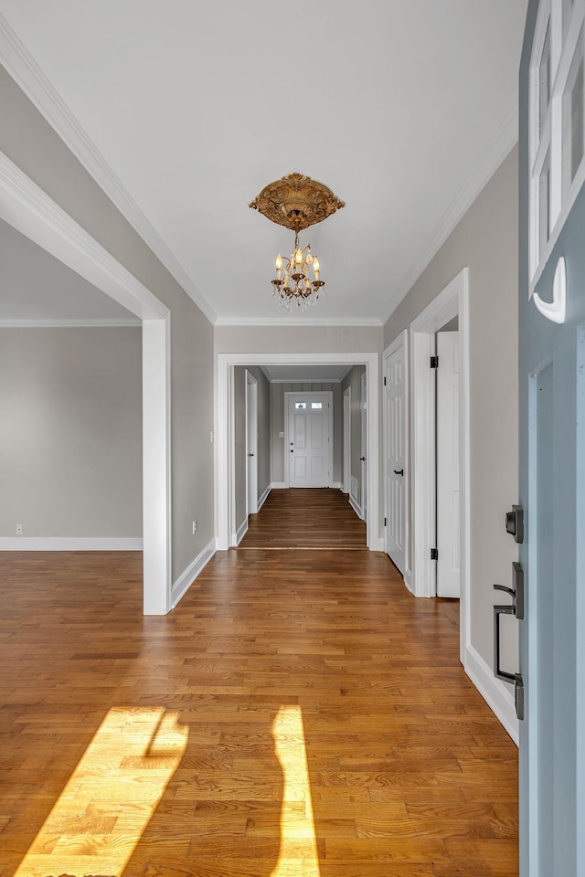 corridor featuring hardwood / wood-style floors, crown molding, and a chandelier