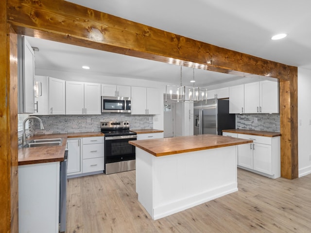 kitchen featuring appliances with stainless steel finishes, white cabinetry, and butcher block counters