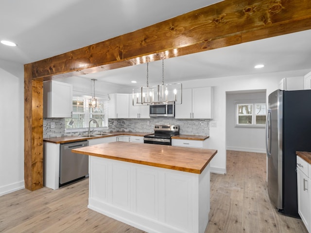 kitchen featuring butcher block counters, white cabinetry, a kitchen island, and stainless steel appliances