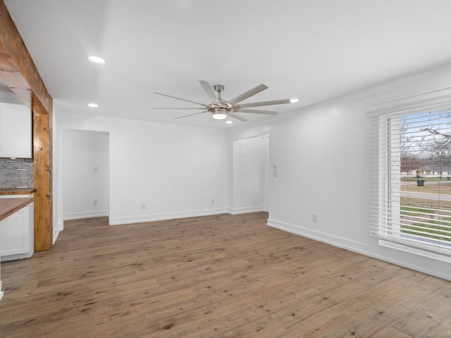 empty room featuring wood-type flooring, plenty of natural light, and ceiling fan