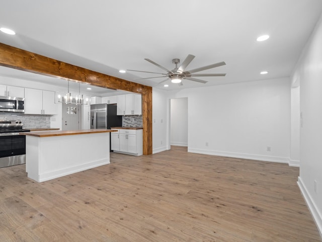 kitchen featuring backsplash, stainless steel appliances, light hardwood / wood-style floors, white cabinetry, and hanging light fixtures