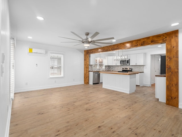 kitchen featuring stainless steel appliances, a wall mounted AC, decorative light fixtures, butcher block countertops, and a kitchen island