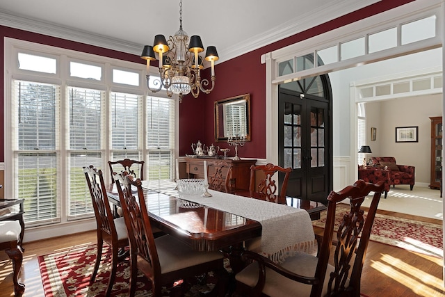 dining area with ornamental molding, wood-type flooring, and a notable chandelier