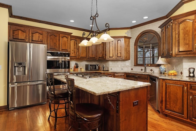 kitchen with a center island, tasteful backsplash, decorative light fixtures, a kitchen bar, and appliances with stainless steel finishes