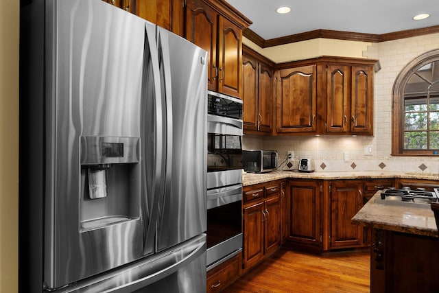 kitchen featuring decorative backsplash, stainless steel fridge, light hardwood / wood-style floors, and light stone counters