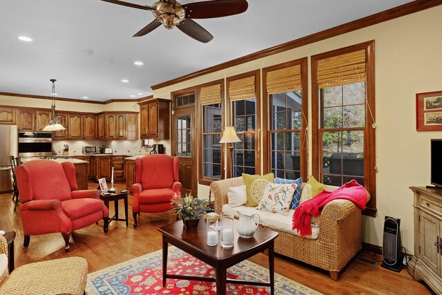 living room with crown molding, light hardwood / wood-style flooring, and ceiling fan