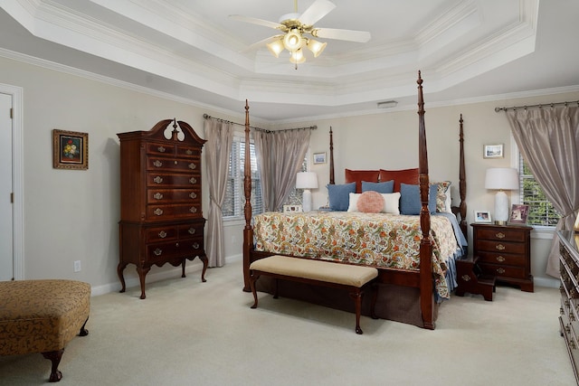 carpeted bedroom featuring a tray ceiling, multiple windows, and crown molding