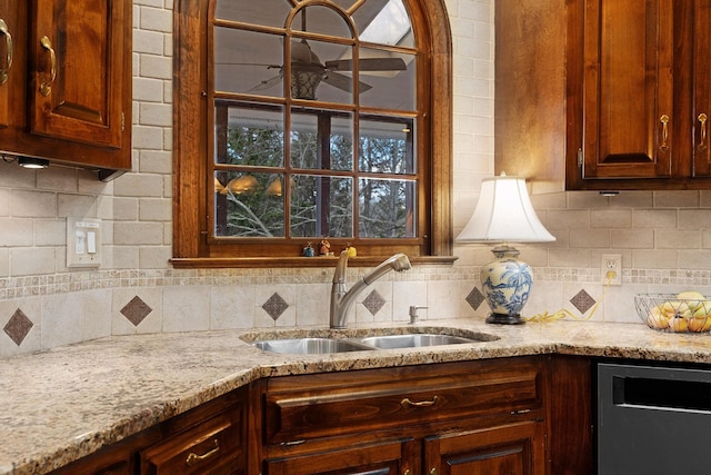 kitchen with stainless steel dishwasher, decorative backsplash, light stone countertops, and sink