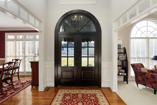 foyer entrance featuring french doors, dark hardwood / wood-style floors, a wall unit AC, and ornamental molding