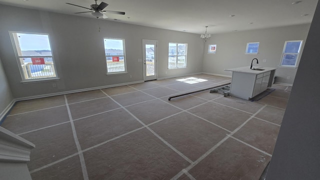 interior space featuring ceiling fan with notable chandelier, light tile patterned flooring, a sink, and baseboards