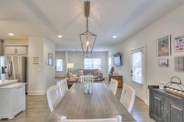 dining area with a wealth of natural light, a notable chandelier, and light wood-type flooring