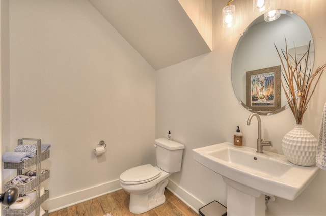 bathroom featuring hardwood / wood-style flooring, toilet, lofted ceiling, and sink