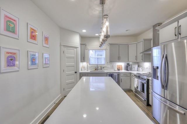 kitchen featuring sink, hanging light fixtures, stainless steel appliances, gray cabinets, and decorative backsplash