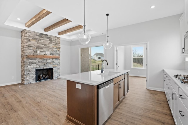 kitchen with a fireplace, white cabinetry, pendant lighting, and stainless steel appliances