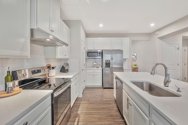 kitchen with decorative backsplash, appliances with stainless steel finishes, light wood-type flooring, sink, and white cabinets