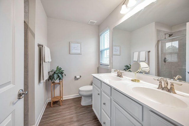 bathroom featuring hardwood / wood-style floors, vanity, toilet, and a shower with shower door