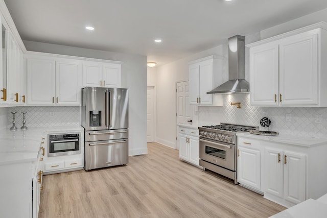 kitchen featuring white cabinets, stainless steel appliances, and wall chimney range hood