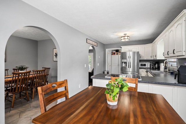 dining area featuring sink, light tile patterned floors, and a textured ceiling