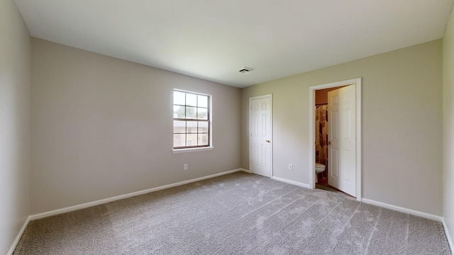 unfurnished bedroom with connected bathroom and light colored carpet